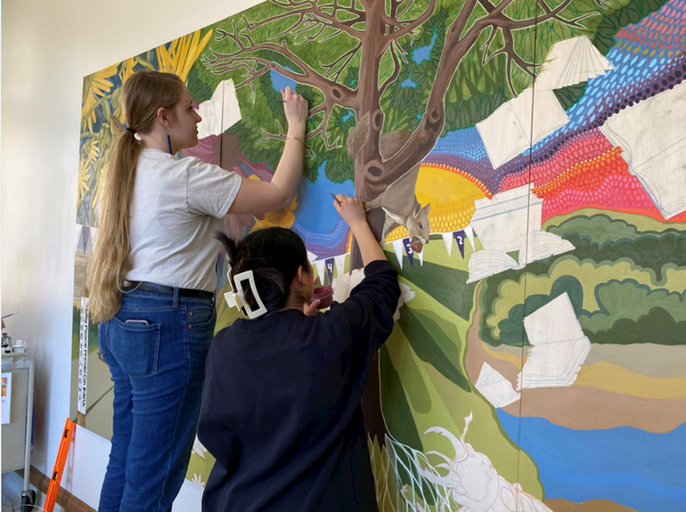 Two students painting a colorful mural