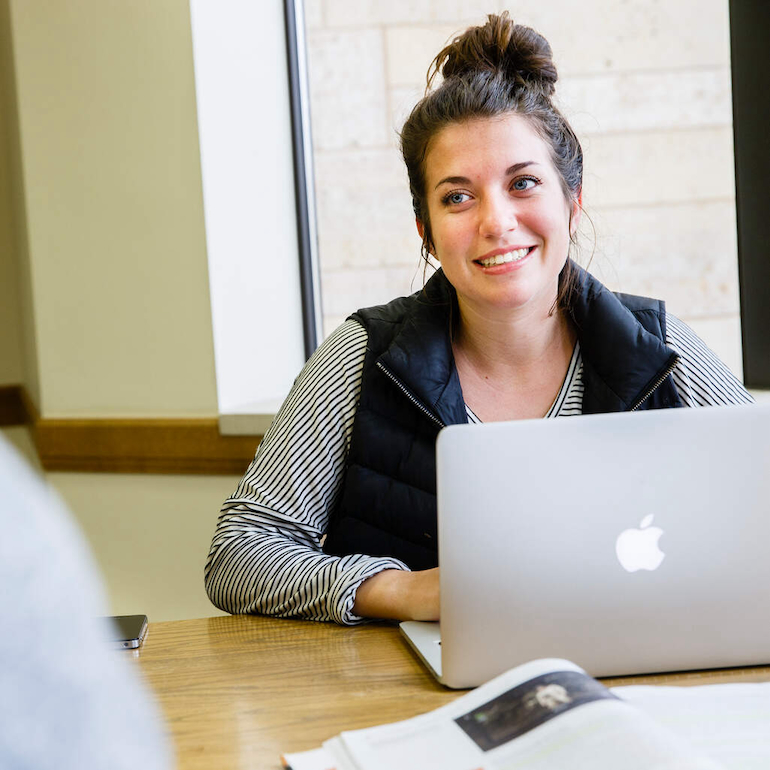 Student smiling at laptop