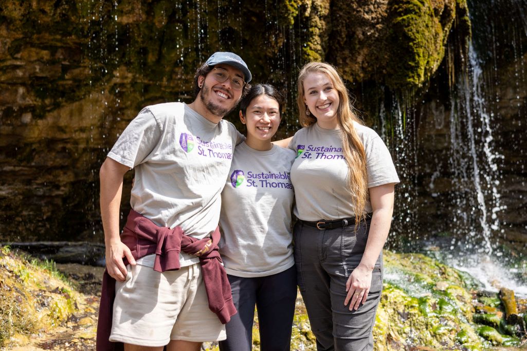 Three students posing with their arms around each other.